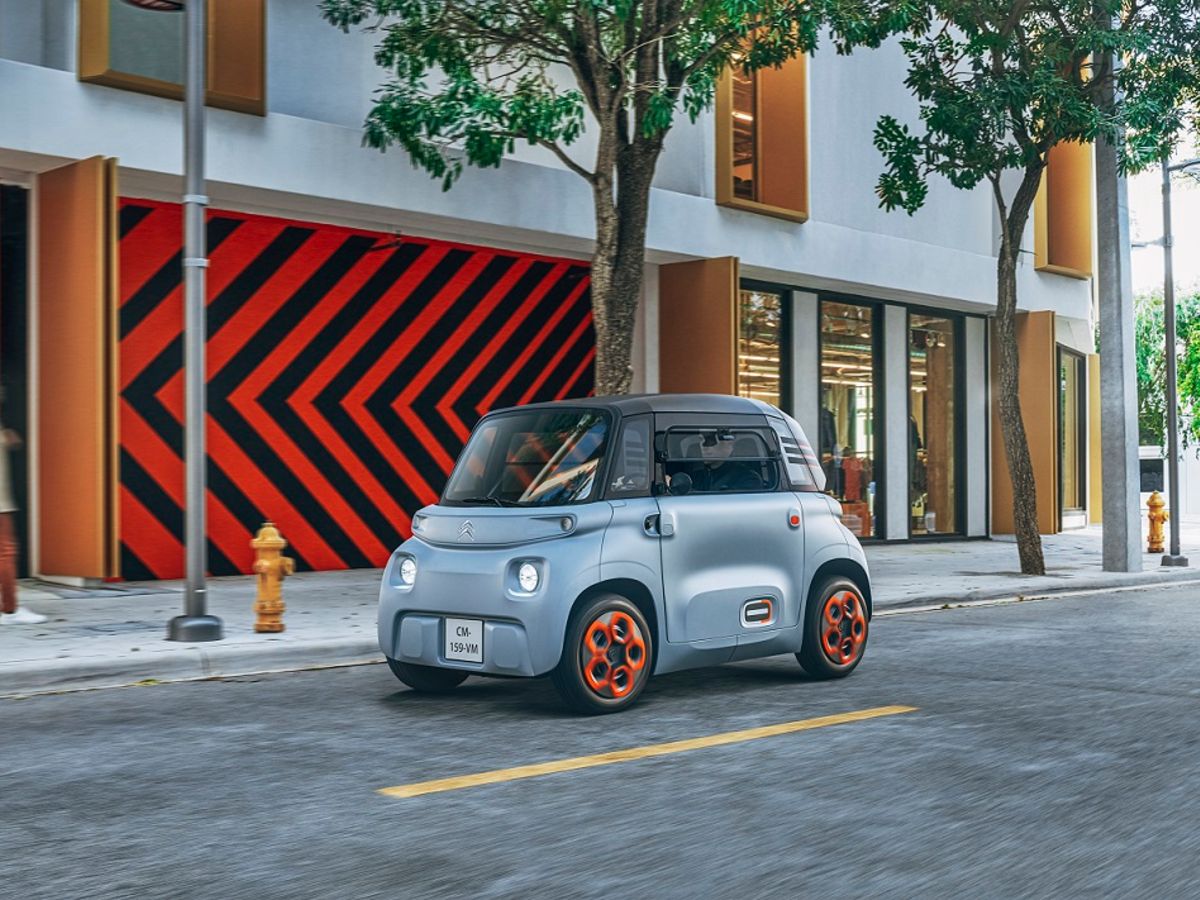 Citroën AMI 100% Elétrico cinzento com pormenores laranja, em locomoção na estrada em cidade